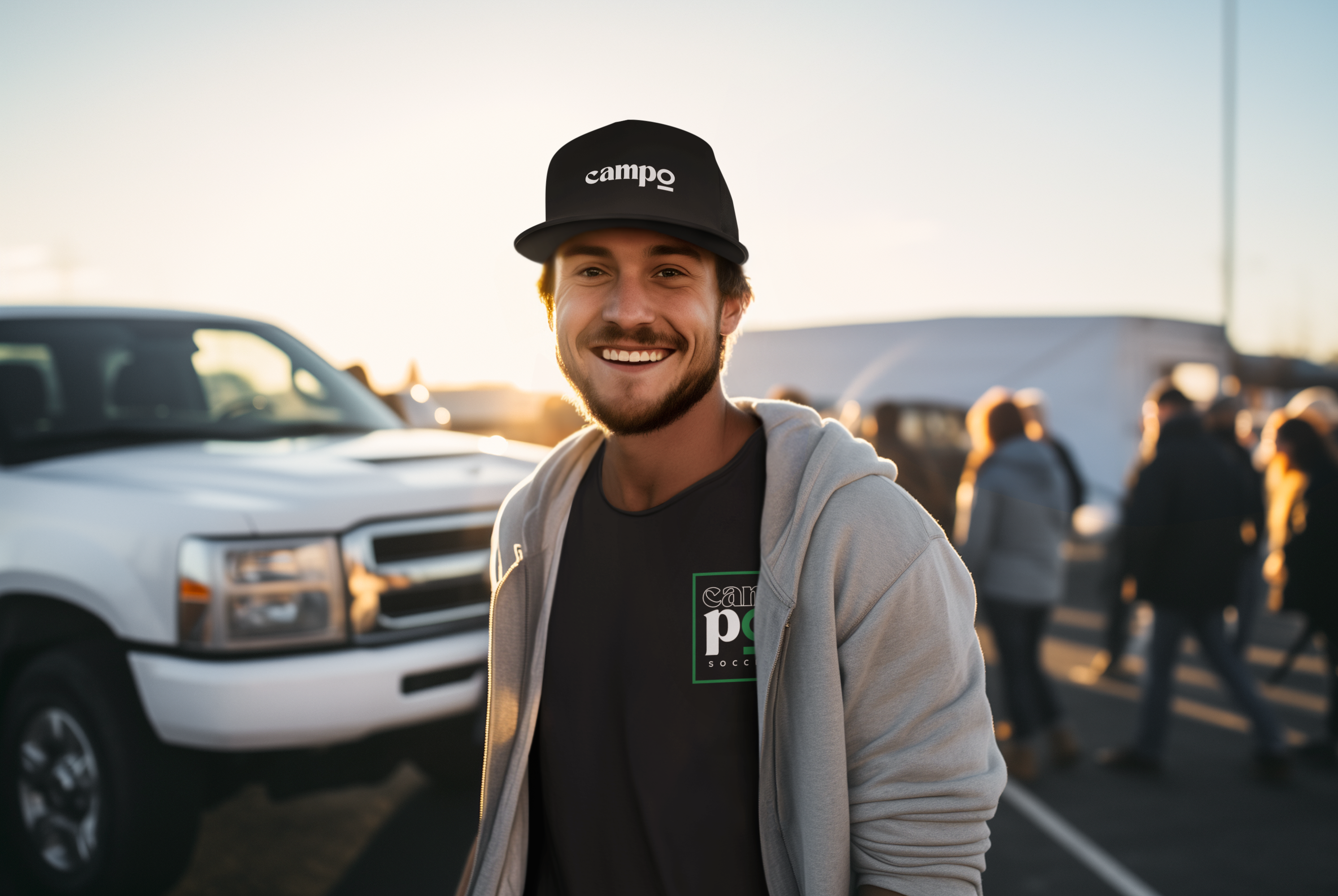 White male smiling at camera wearing a black trucker hat in a stadium parking lot.